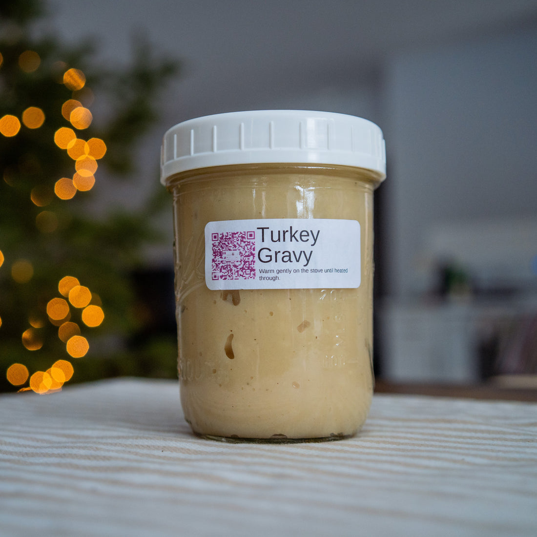 Jar of turkey gravy with a label on a table with a blurred background